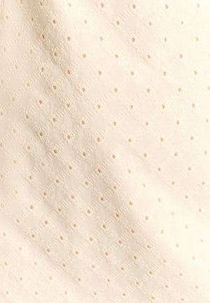 Hvidt stof med et diamantmønster og små udskårne huller, der har tekstureret overfladedetaljering, hvilket skaber et let udseende.