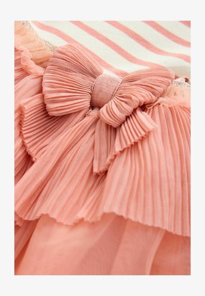 Dettaglio di un vestito arricciato con tessuto plissettato color corallo, un grande fiocco decorativo e un motivo a righe sottili in una combinazione di colori crema e corallo.