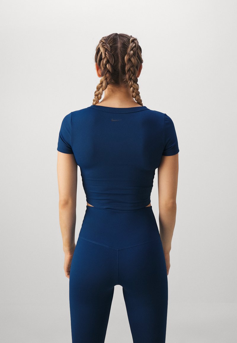 Een marineblauw sportoutfit bestaande uit een aansluitend, kort mouwtop met een ronde halslijn en hoge taille legging, beide gemaakt van een gladde stof.