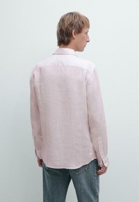 Lichtroze linnen shirt met lange mouwen, een kraag halslijn en knoopmanchetten. Droeg het met lichtgrijze spijkerbroek.