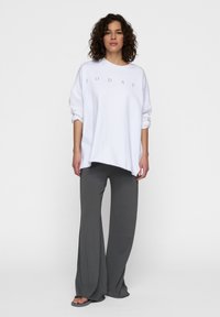 Sudadera blanca de gran tamaño con el texto negro "10 DÍAS" y pantalones de pierna ancha grises. Tejido suave, corte relajado y diseño casual.