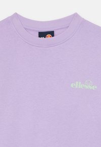 Fialová mikina vyrobená z bavlny s žebrovaným výstřihem. Na hrudi má světlezelené logo 'ellesse'. Hladká textura, ležérní design.
