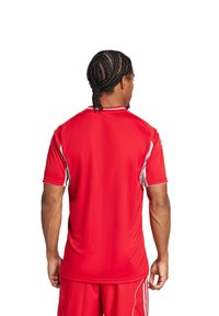 Maglietta sportiva rossa con maniche corte, dettagli bianchi e scollatura rotonda. Il tessuto sembra liscio e traspirante.