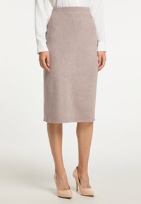 Strick-Bleistiftrock in hellem Taubengrau mit gerippter Textur, knielang und mit tailliertem Bund. Kombiniert mit nudefarbenen High Heels.