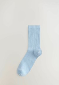 Vaaleansininen ribbineulottu puuvillasukka, jossa on saumaton varvasosa, nilkkapituus ja pehmeä tekstuuri, esitetty neutraalilla taustalla.