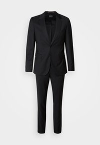 Črn kostim, ki je sestavljen iz enojno zapenjalne jakne s šalom na reverju in usklajenih hlač. Narejen iz gladkega blaga, prilega se telesu.