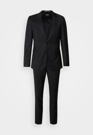 Schwarzer Anzug, bestehend aus einem einreihigen Jacket mit Schalkragen und passender Hose. Hergestellt aus glattem Stoff, taillierter Schnitt.