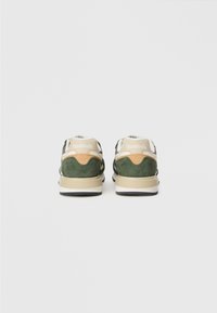 Sporta apavi ar zaļu zamšas virsu, bēšiem un brūniem akcentiem, kā arī baltu mēli. Iezīmēta ar tekstūrētu gumijas zoli un Reebok zīmolu aizmugurē.