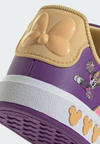 Fioletowy tenisówka z fakturowaną białą podeszwą, błyszczącą beżową kokardką i nadrukiem postaci po boku.