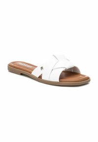 Chanclas blancas de slide con tiras cruzadas, que presentan una textura lisa y una plantilla marrón. Diseño minimalista con suela de goma de perfil bajo.