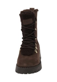 Bruine suède laars met een fluffy textielen kraag, metalen oogjes en een dikke rubberen zool met diepe noppen. Veters lopen door gouden accenten.