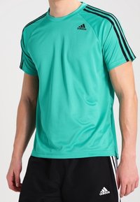 Turquoise athletic t-shirt with black stripes on shoulders. Made from lightweight fabric, features logo on chest, and a rounded neckline.