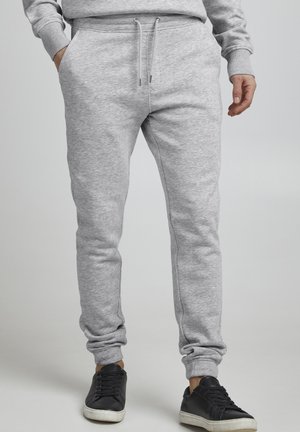 Gray sweatpants made of soft, textured fabric. Features an elastic waistband with adjustable drawstrings and side pockets. Slim fit design.