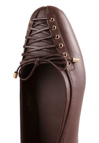 Chaussure plate en cuir marron avec bout carré arrondi et lacets décoratifs croisés attachés en nœud, ornée d'œillets dorés et d'embouts de lacet dorés.