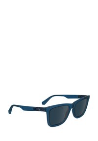 Ochelari de soare cu un cadru din plastic de culoare albastru profund, lentile întunecate și formă pătrată. Au un logo argintiu pe bradă și linii elegante.