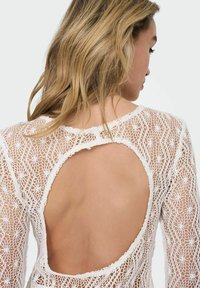 Spitzenoberteil mit langen Ärmeln in Weiß, mit einem kunstvollen floralen Muster, tiefem Rückenausschnitt und gewelltem Halsausschnitt.