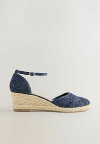 Espadrille compensée bleu marine avec bride à la cheville, présentant des détails brodés complexes et une semelle en jute tissé.