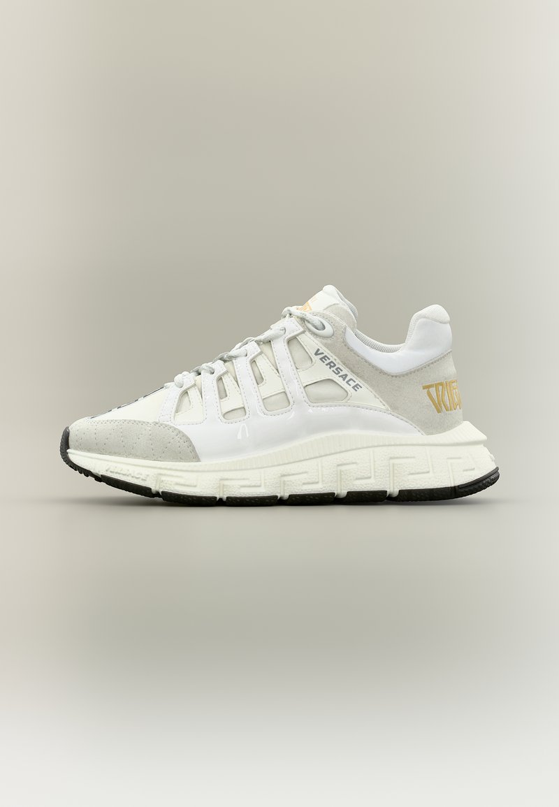 Baskets Versace blanches et grises avec un design à lacets, semelle épaisse ornée d'un motif clé grec, et détail du logo doré sur le talon.