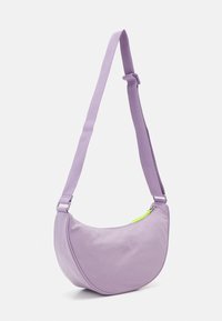 Bolso de hombro de tela morada con forma curva, correa ajustable y detalle de cremallera en verde neón. Textura suave y diseño minimalista.