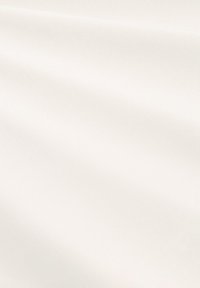 Cremefarbener Baumwollstoff mit glatter Textur, weichem Glanz und leichter Drapierung, der subtile Variationen in der Oberfläche und Falten aufweist.