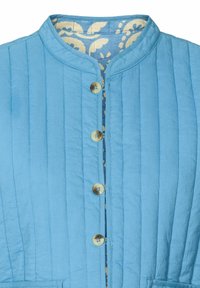 Giacca trapuntata azzurro chiaro con collo rotondo, bottoni frontali e una fodera floreale beige visibile all'interno. Presenta cuciture verticali e tasche.