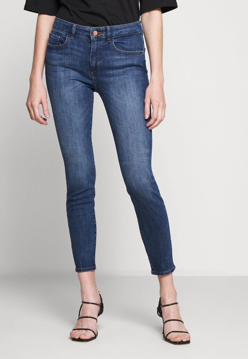 Dunkelblaue Skinny Jeans aus Denim mit hoher Taille, feinen Nähten und zwei Vorderaschen. Der Schnitt ist eng am Bein.