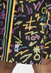 Pantaloncini neri con un motivo astratto colorato che presenta varie forme. Dettagli importanti includono strisce laterali multicolori e un logo ricamato.