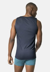 T-shirt de sport sans manches bleu marine en tissu texturé, avec un col rond et une coupe athlétique, associé à un short turquoise.