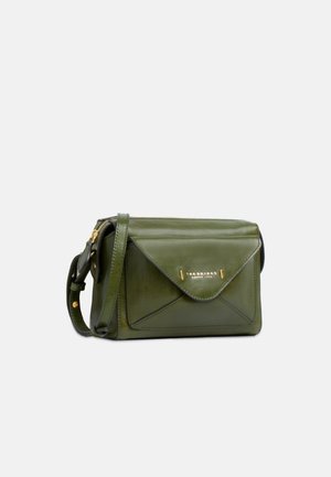 Donkergroene leren crossbodytas met voorkant enveloppenvak en goudkleurige logo- en ritsdetails op een lichte achtergrond.
