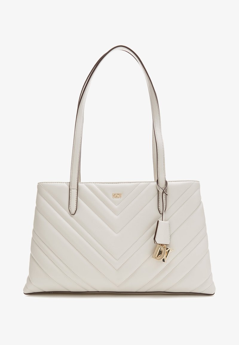 Sac à main en cuir matelassé crème avec motif en chevron, double bandoulières et charm DKNY en or suspendu à une bandoulière.