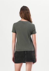 Kortärmad, olivgrön t-shirt i mjukt material, med rund halsringning och något figursydd design, i kombination med en svart denimkjol.