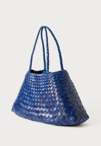 Υφασμένη μπλε δερμάτινη τσάντα ώμου με πλεγμένες λαβές, τρίγωνο σχήμα και υφή που παρουσιάζει ένα πατιναρισμένο σχέδιο.