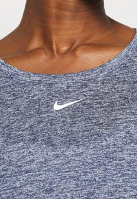 Námořnická modrá sportovní košile s melírovanou texturou, s bílým logem Nike na hrudi a kulatým výstřihem.