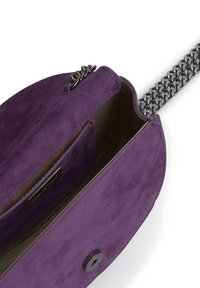 Fioletowa zamszowa torebka na łańcuszku, z wewnętrzną kieszenią i magnetycznym zapięciem. Gładka tekstura i zorganizowany kształt.