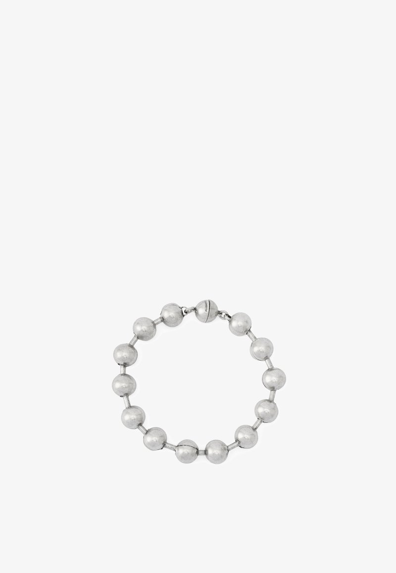 Bracelet en métal argenté avec des perles rondes reliées par de petites barres et un fermoir sphérique gravé du nom de la marque, présenté sur fond blanc.