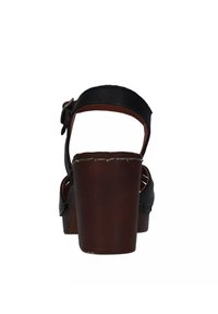 Sandali neri in pelle con tacco a blocco in legno marrone, cinturino alla caviglia regolabile e dettagli cuciti sulla suola.