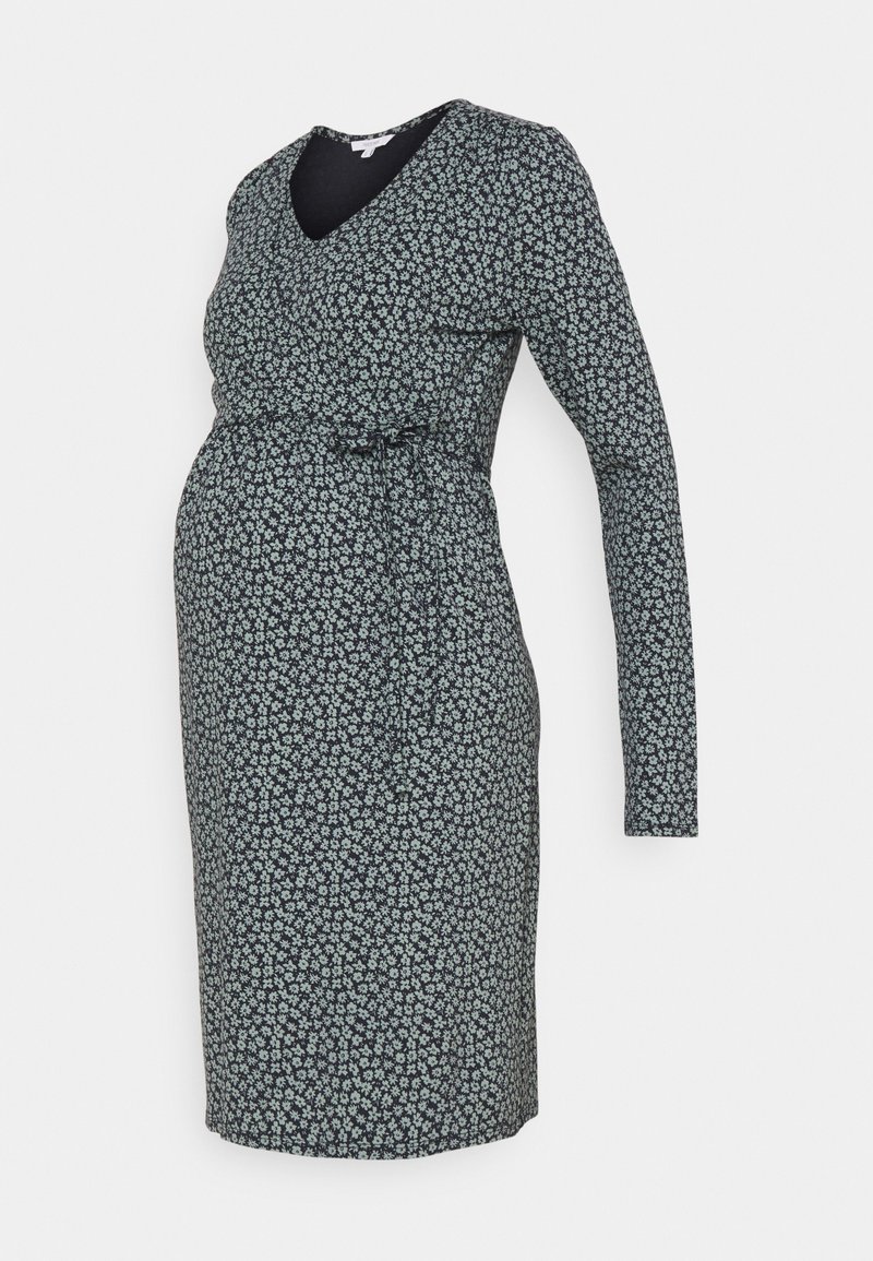 Robe de maternité à manches longues avec petit motif floral blanc sur fond foncé, taille cintrée avec lien latéral, longueur genou.