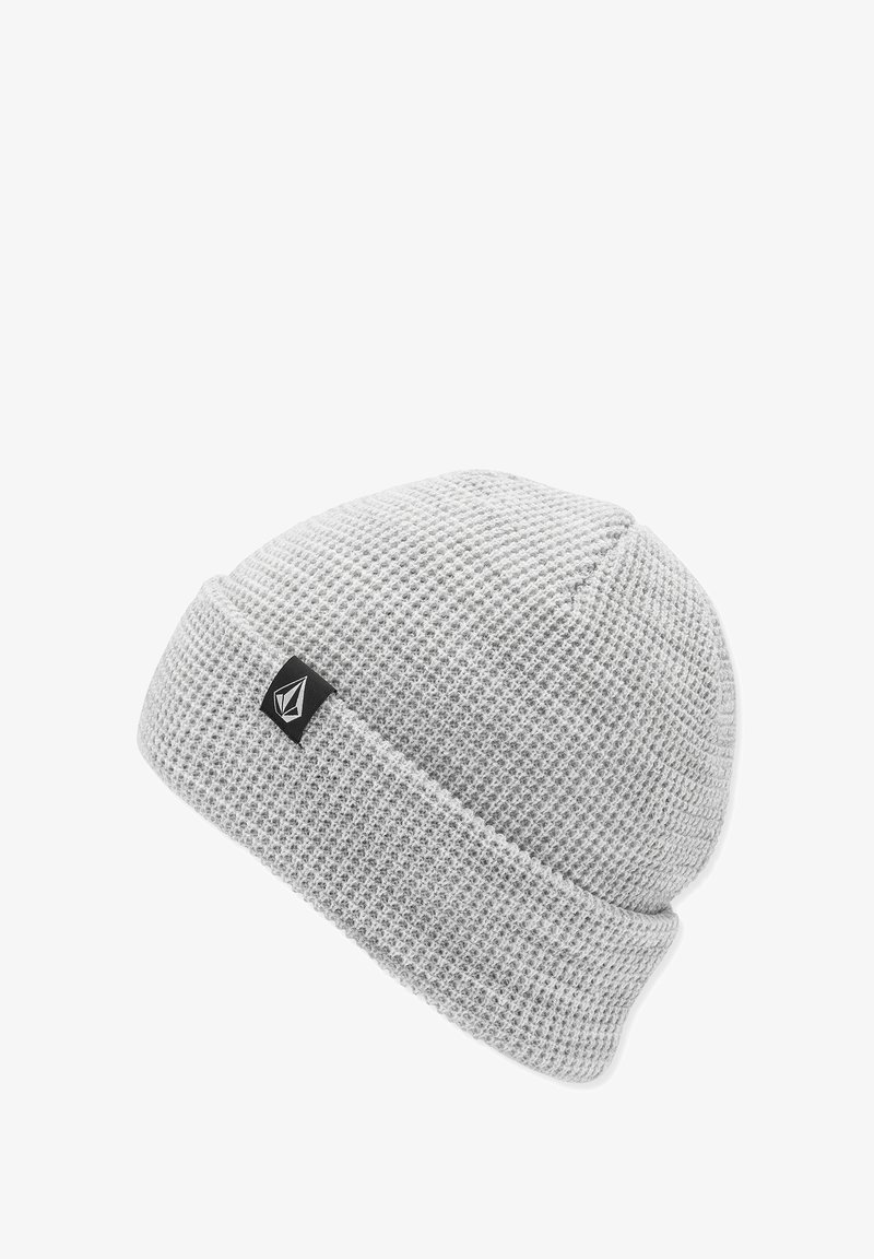 Bonnet en tricot gris, avec un motif texturé, un revers replié et une petite étiquette logo noire sur le côté.