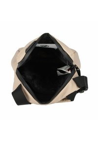 Beige softshell-väska med svarta accenter. Dragkedjeöppning avslöjar ett svartfodrat inre. Har justerbara remmar och ett märke inuti.