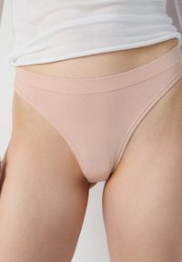 Perizoma rosa chiaro con una morbida fascia in vita senza cuciture, realizzato in un tessuto misto cotone liscio, caratterizzato da un design minimalista.