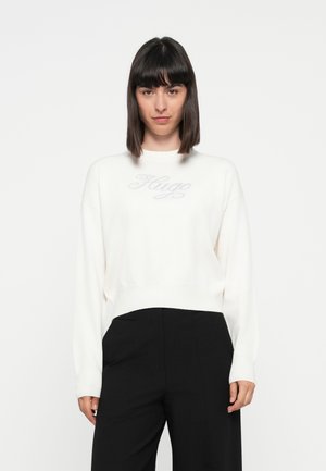 Witte gebreide sweatshirt met een ronde hals, voorzien van een subtiele 'Hugo' logo in grijs op de borst. Gecombineerd met zwarte wijde broek.