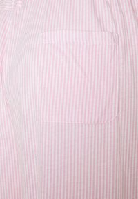 Roze en witte gestreepte stof met een patchzak. De stof lijkt lichtgewicht en zacht met verticale strepen en afgewerkte randen.
