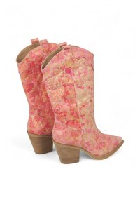 Botas de vaquero rosas con un patrón veteado, acabado texturizado, punta puntiaguda y un tacón de madera apilada. Costuras decorativas a lo largo de los bordes.