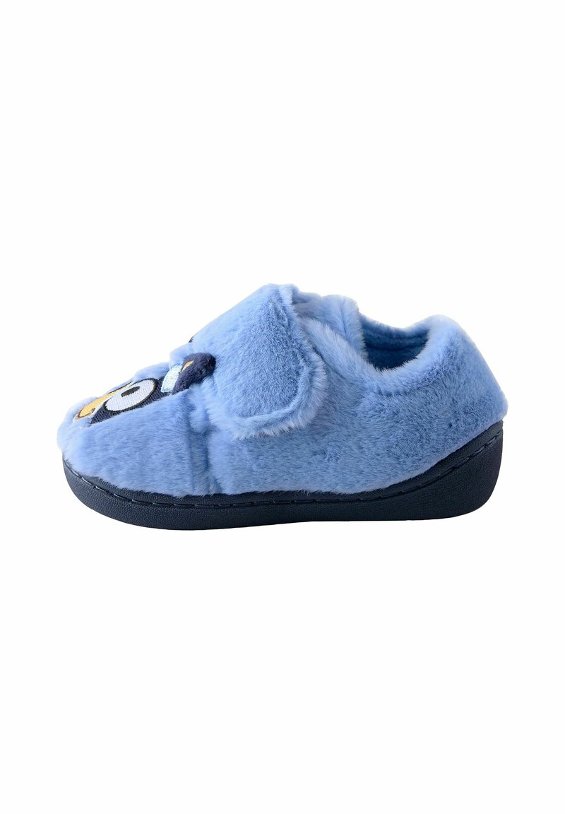 Chaussons moelleux bleus avec une surface texturée, présentant un design de dessin animé sur le devant, et une semelle en caoutchouc noir pour l'adhérence.