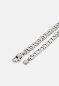 Sølvmetallkjede med store ledd, med lås og en liten anheng. Glatt tekstur og polert overflate.