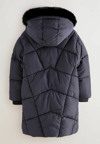 Cappotto imbottito blu scuro con cappuccio e rifinitura in pelliccia sintetica nera, motivo a cuciture diagonali e polsini a coste. La vista da dietro mostra i dettagli del design.