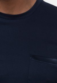 Mörkblå t-shirt i mjukt tyg, med rundad halsringning och en bröstficka med en satinlika yta.