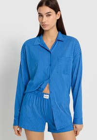 Blårandig pyjamas set som består av en långärmad knäppskjorta med ficka och matchande shorts med elastisk midja.