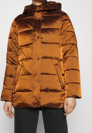 Person wearing a shiny rust-orange quilted puffer jacket with snap buttons, side pockets, and an attached hood, paired with black pants.