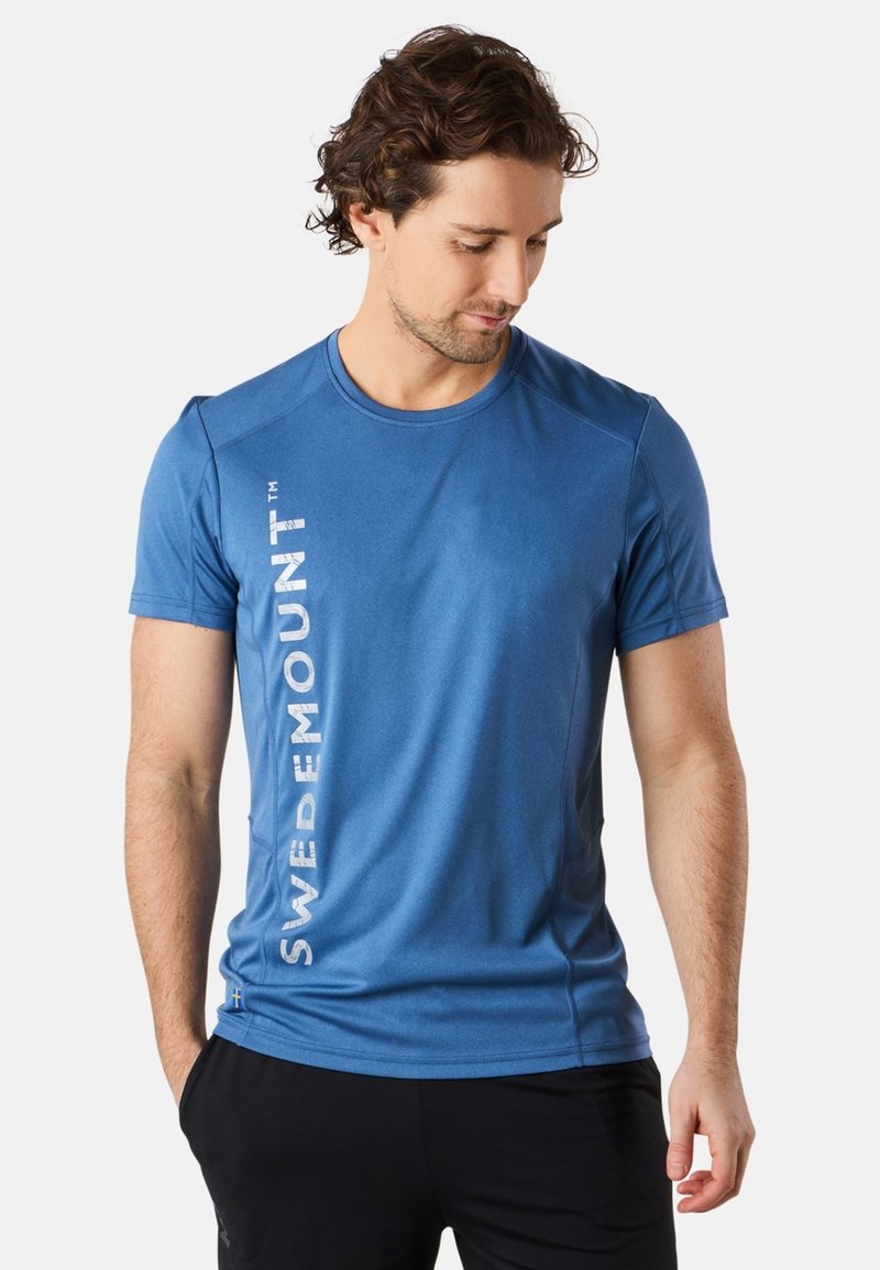 Blå tränings t-shirt tillverkad av lättviktigt material, med rund halsringning och vertikal vit text "SWEDMOUNT" på vänster sida.